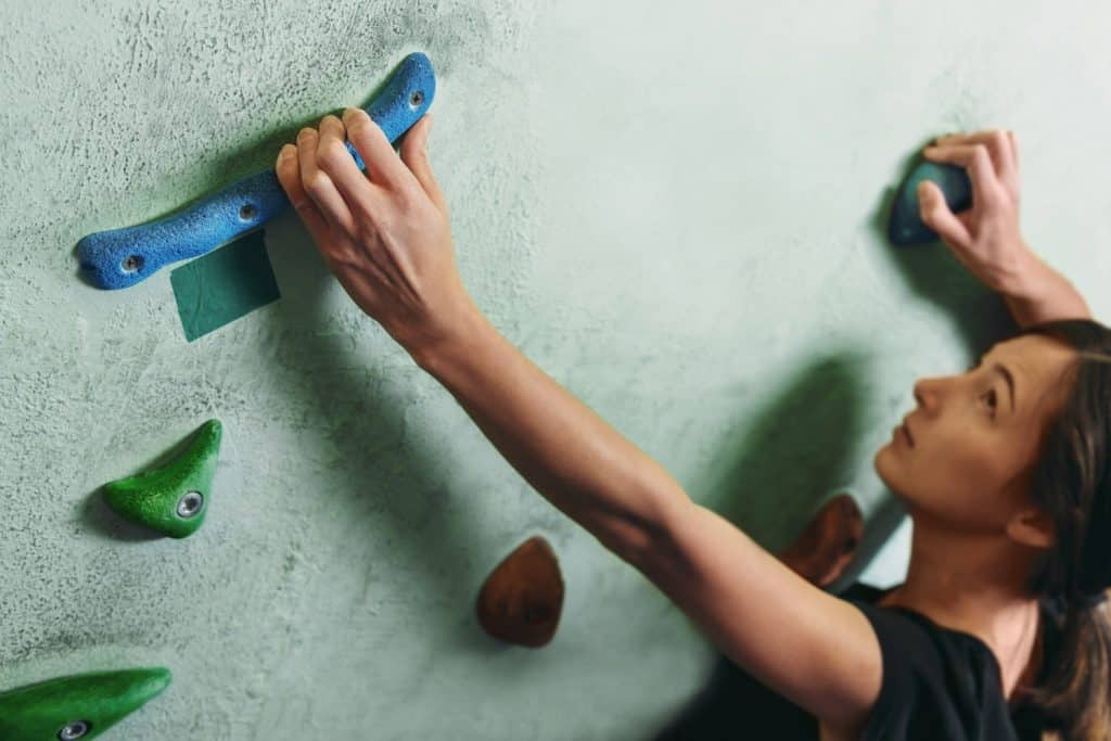 A woman gripping onto a rock wall with her fingertips. 