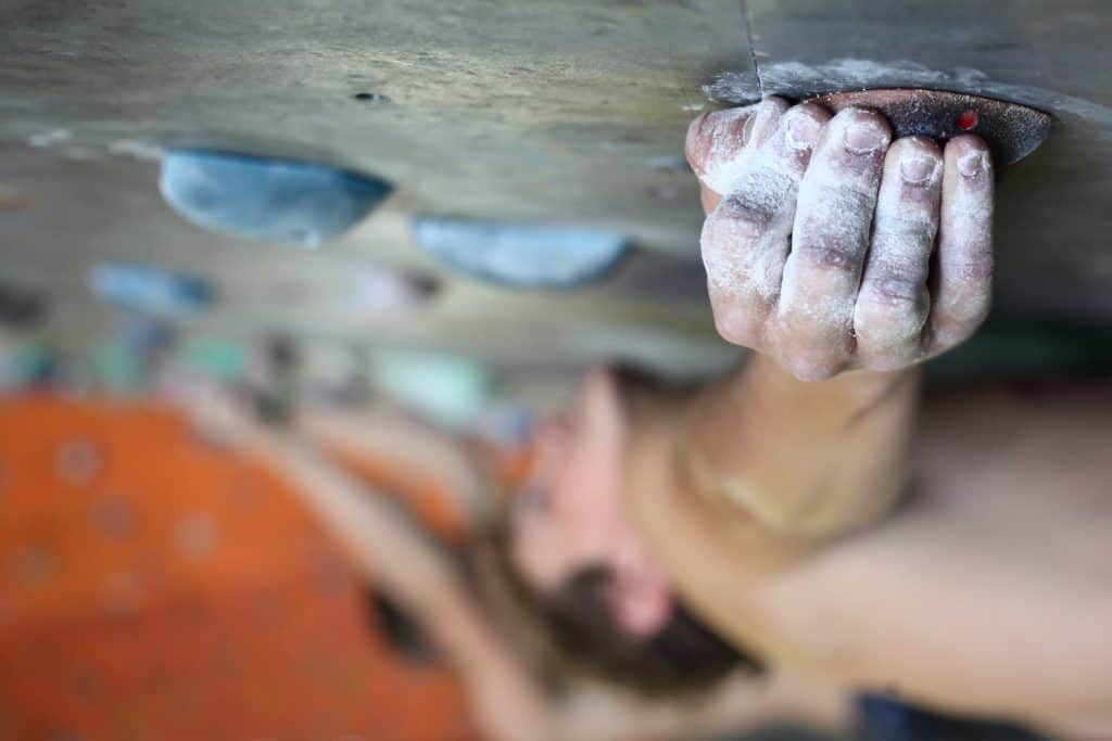 Close up view of a chalked hand gripping a rock wall. 