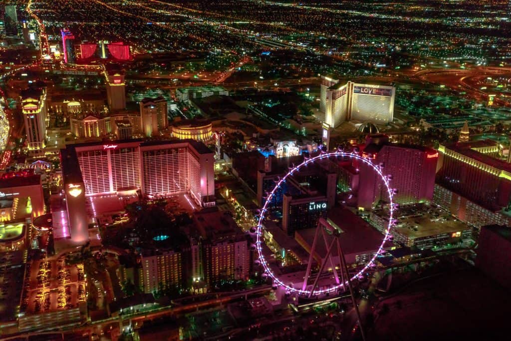 View of the Las Vegas strip at night with a ferris wheel lit up. 
