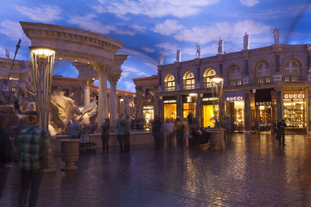 Indoor shops with a cloud ceiling and Greek style storefronts. 
