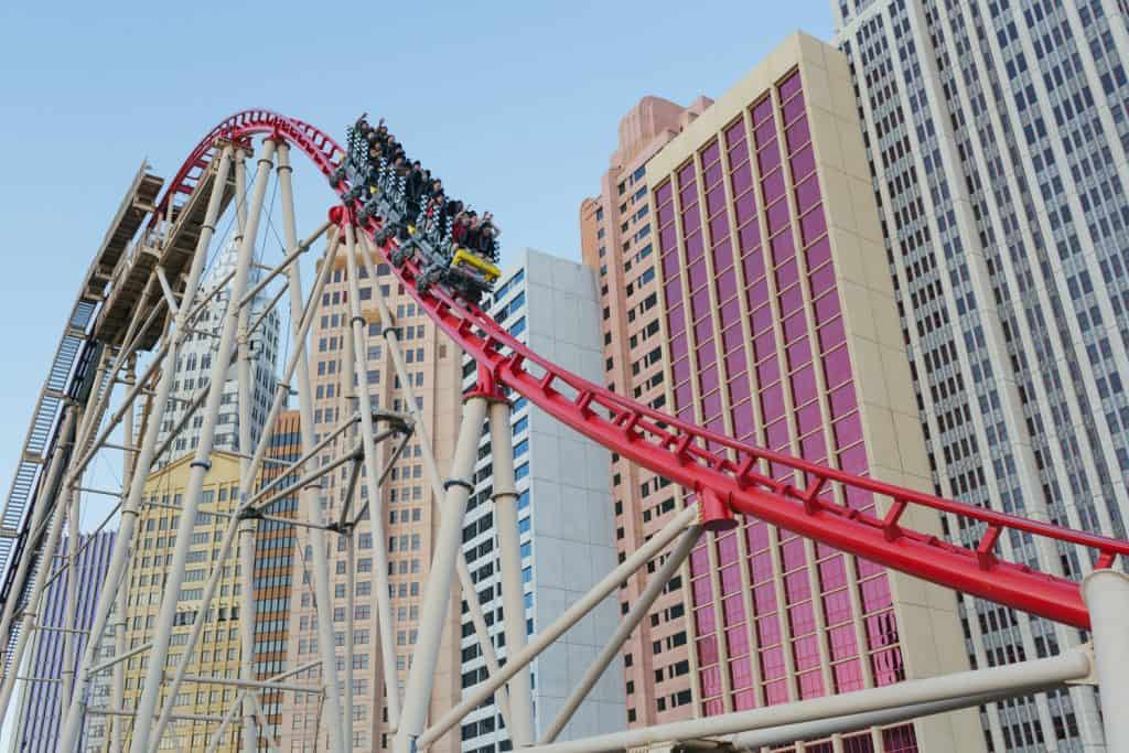 A roller coaster in front of a hotel that looks like New York City skyscrapers. 