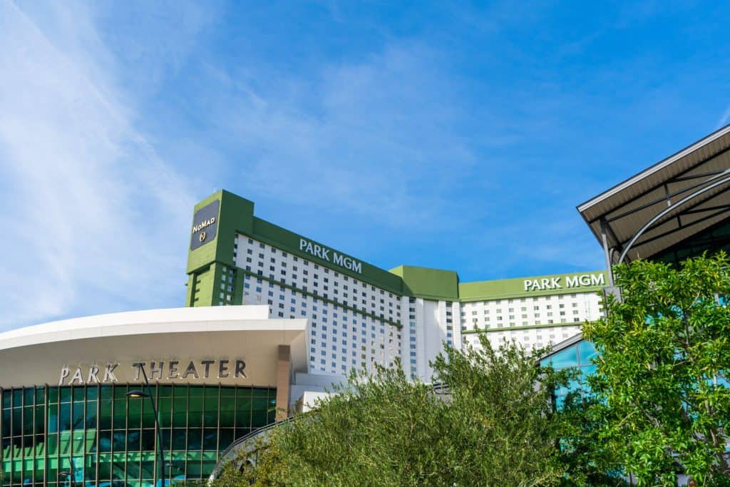 Trees in front of a large resort and theater with letters on the top that read "Park MGM".